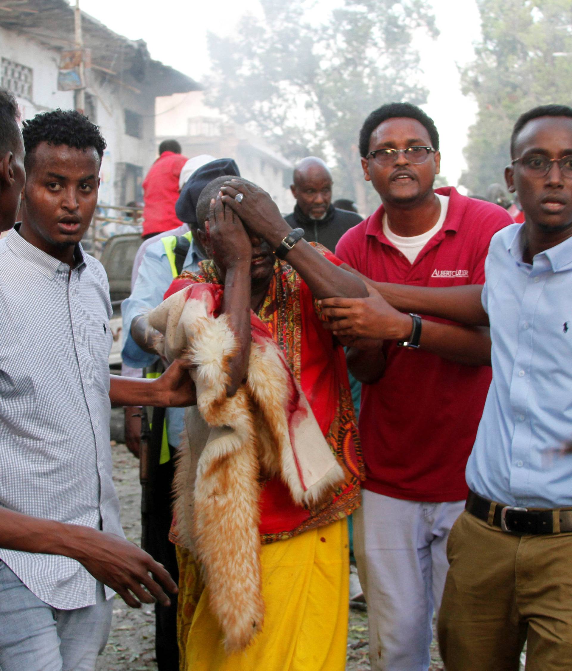 Civilians assist a man injured from the scene of a suicide car bombing at the gate of Naso Hablod Two hotel in Mogadishu