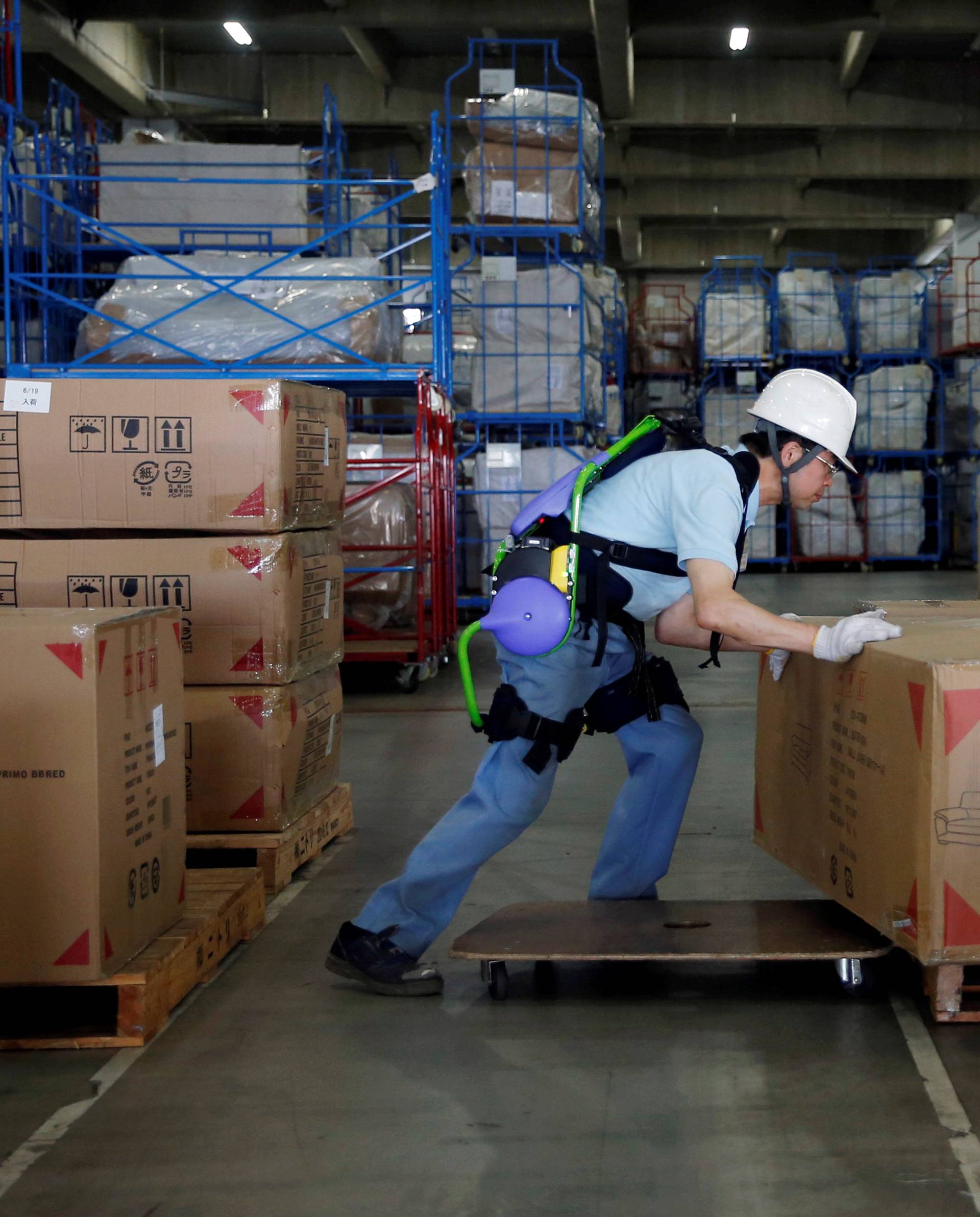 Okutani, 57, a contract worker of Ueda Co., Ltd., wears an Atoun Inc. Power Assist Suit, as he works at a distribution center in Kawasaki