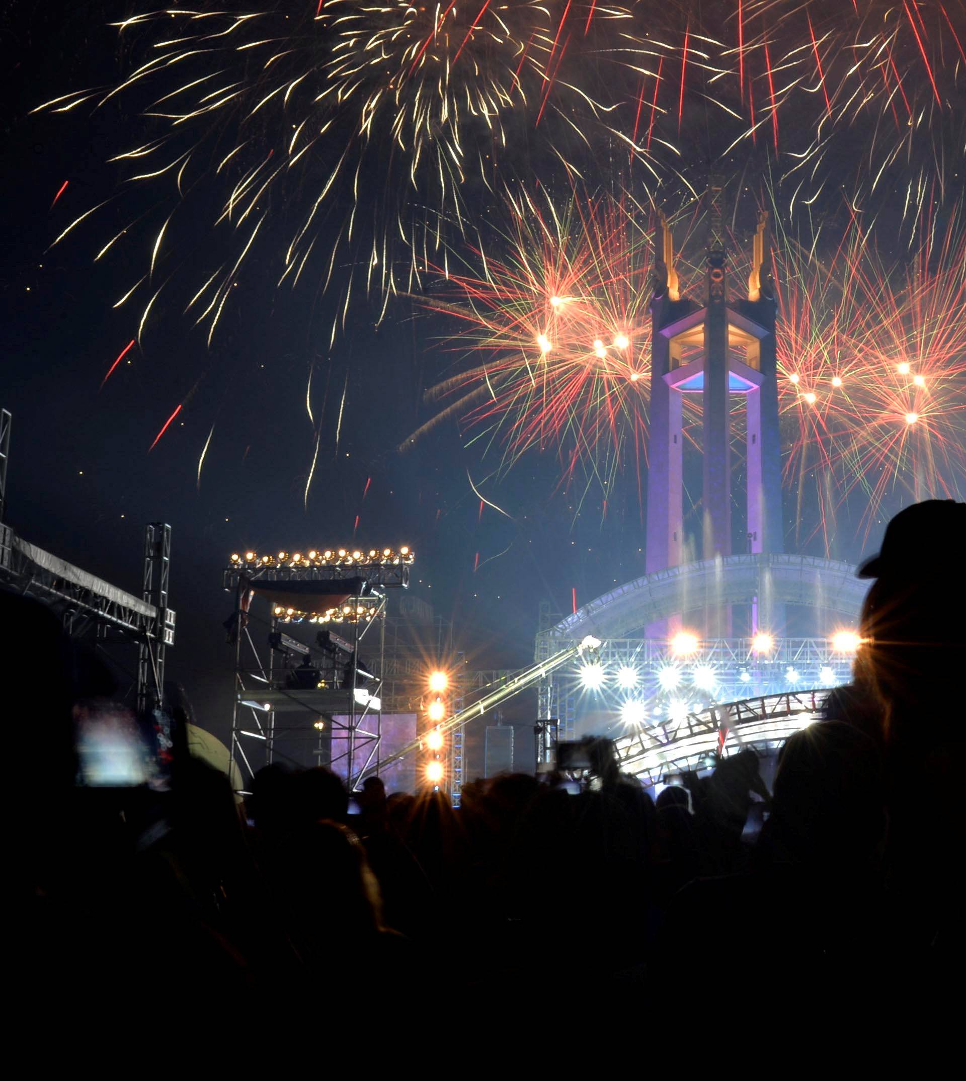 Revellers watch as fireworks explode over the Quezon Memorial Circle during New Year's celebrations in Quezon City, Metro Manila