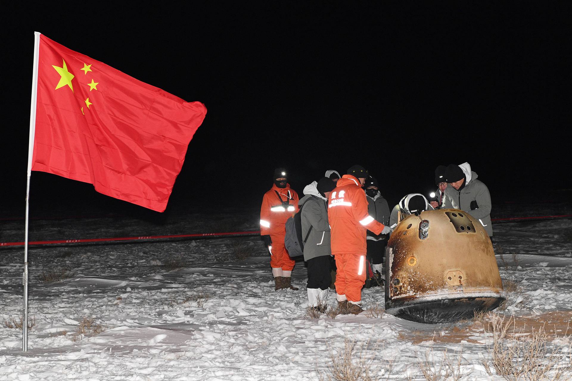 Researchers work around Chang'e-5 lunar return capsule carrying moon samples next to a Chinese national flag, after it landed in northern China's Inner Mongolia Autonomous Region