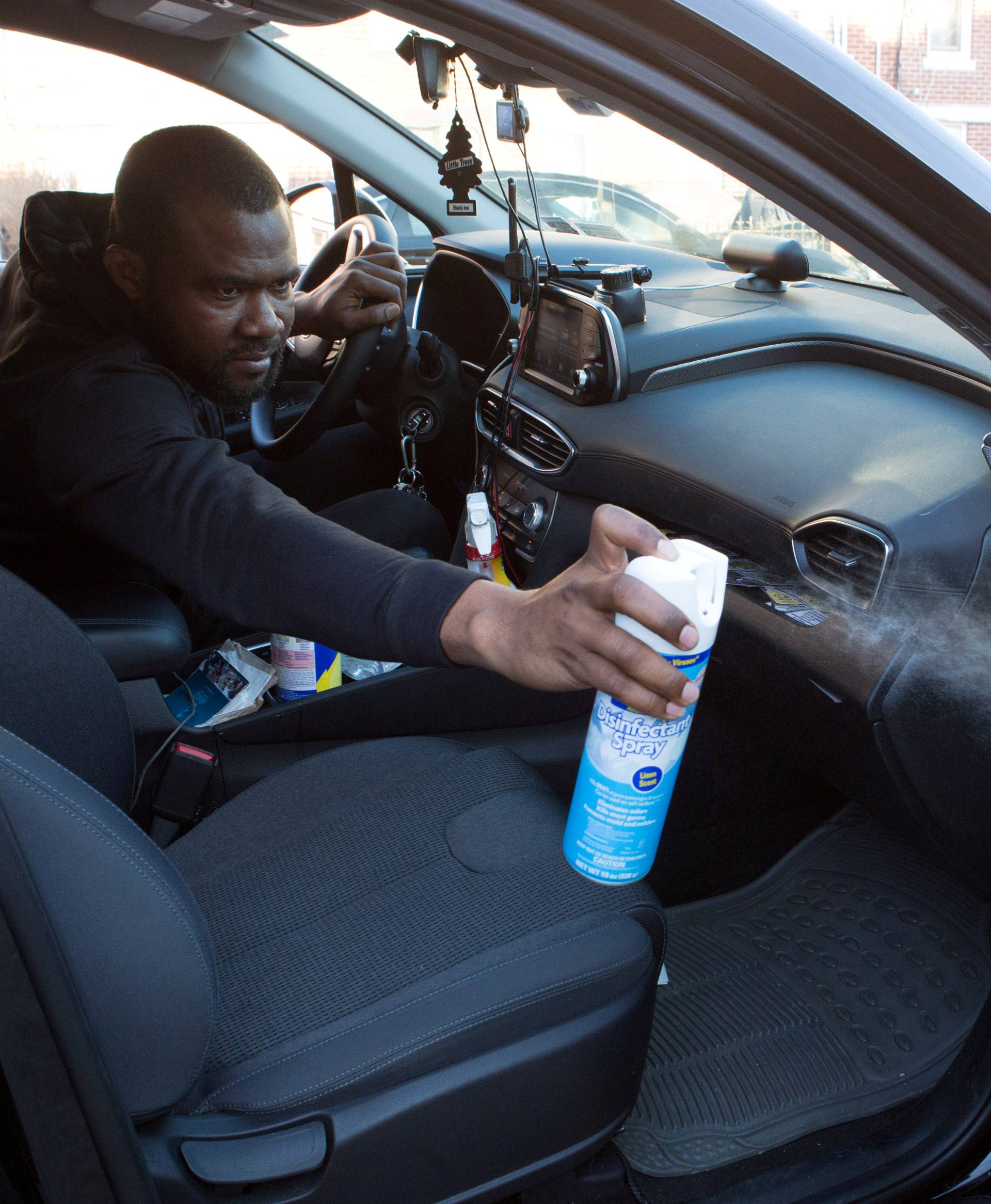 FILE PHOTO: Uber and Lyft driver Adama Fofana sprays disinfectant in his car in New York City