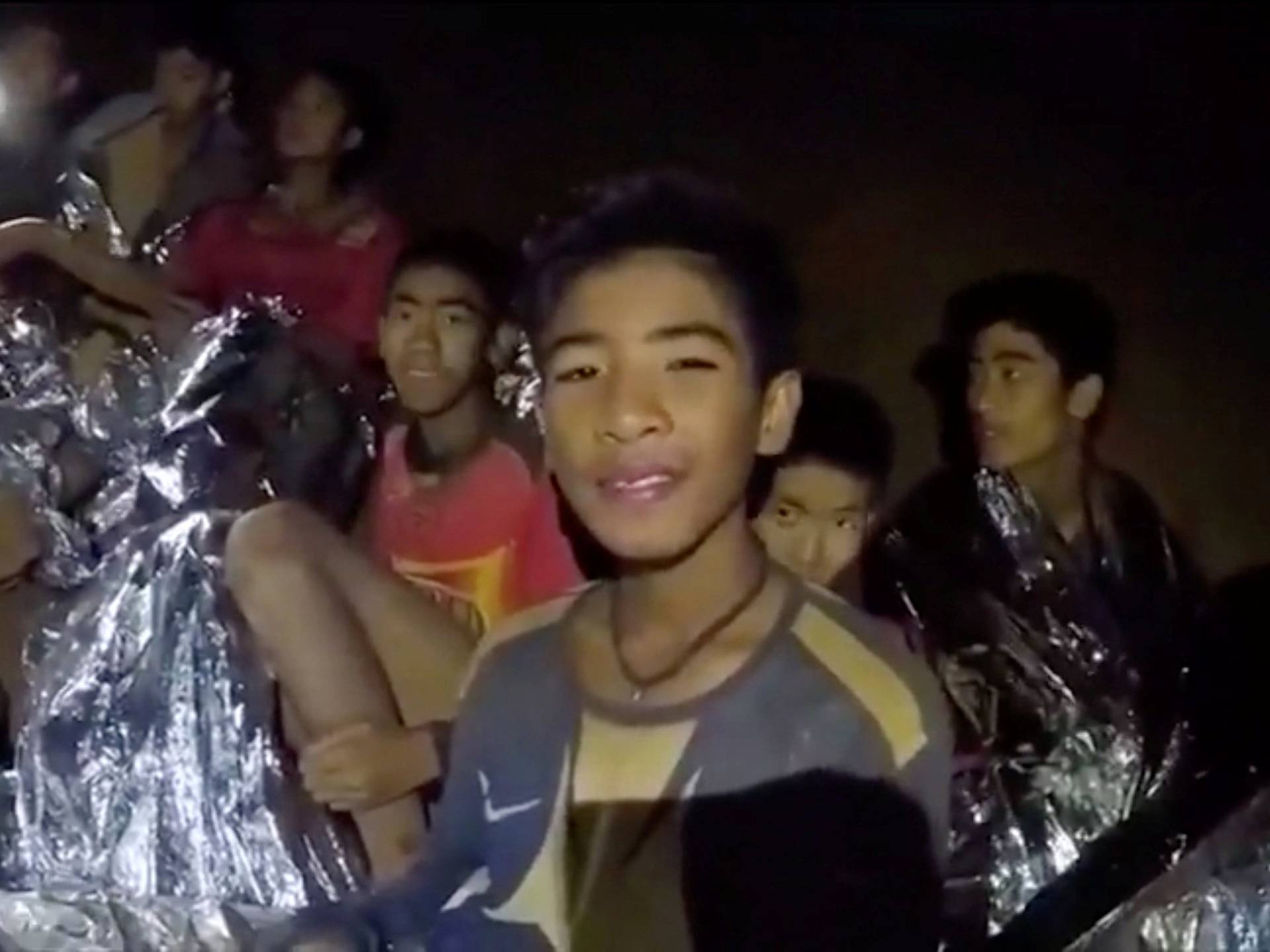 Boys from the under-16 soccer team trapped inside Tham Luang cave covered in hypothermia blankets react to the camera in Chiang Rai, Thailand