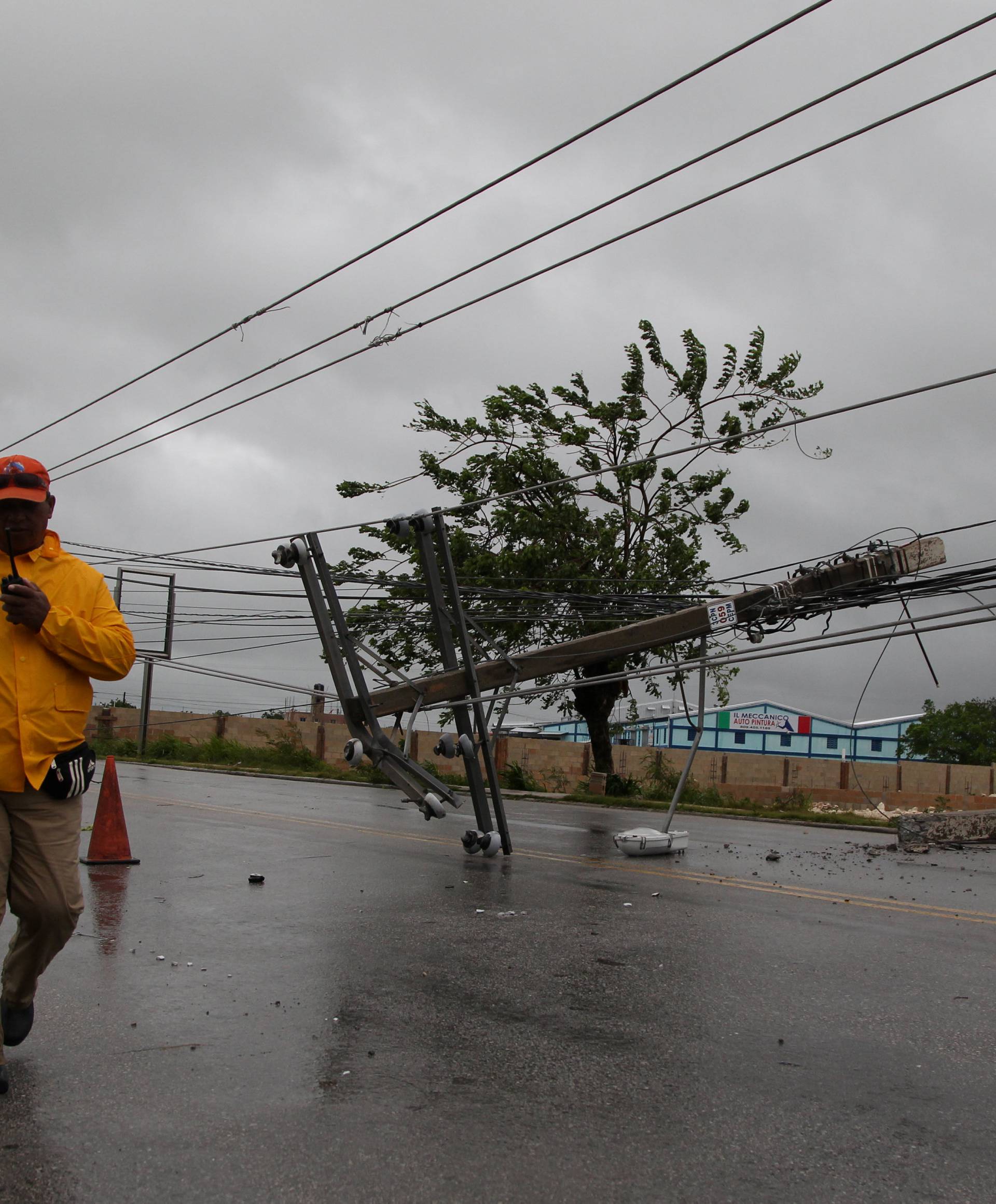 A worker walks past a fallen power pole before the arrival of Hurricane Maria in Punta Cana