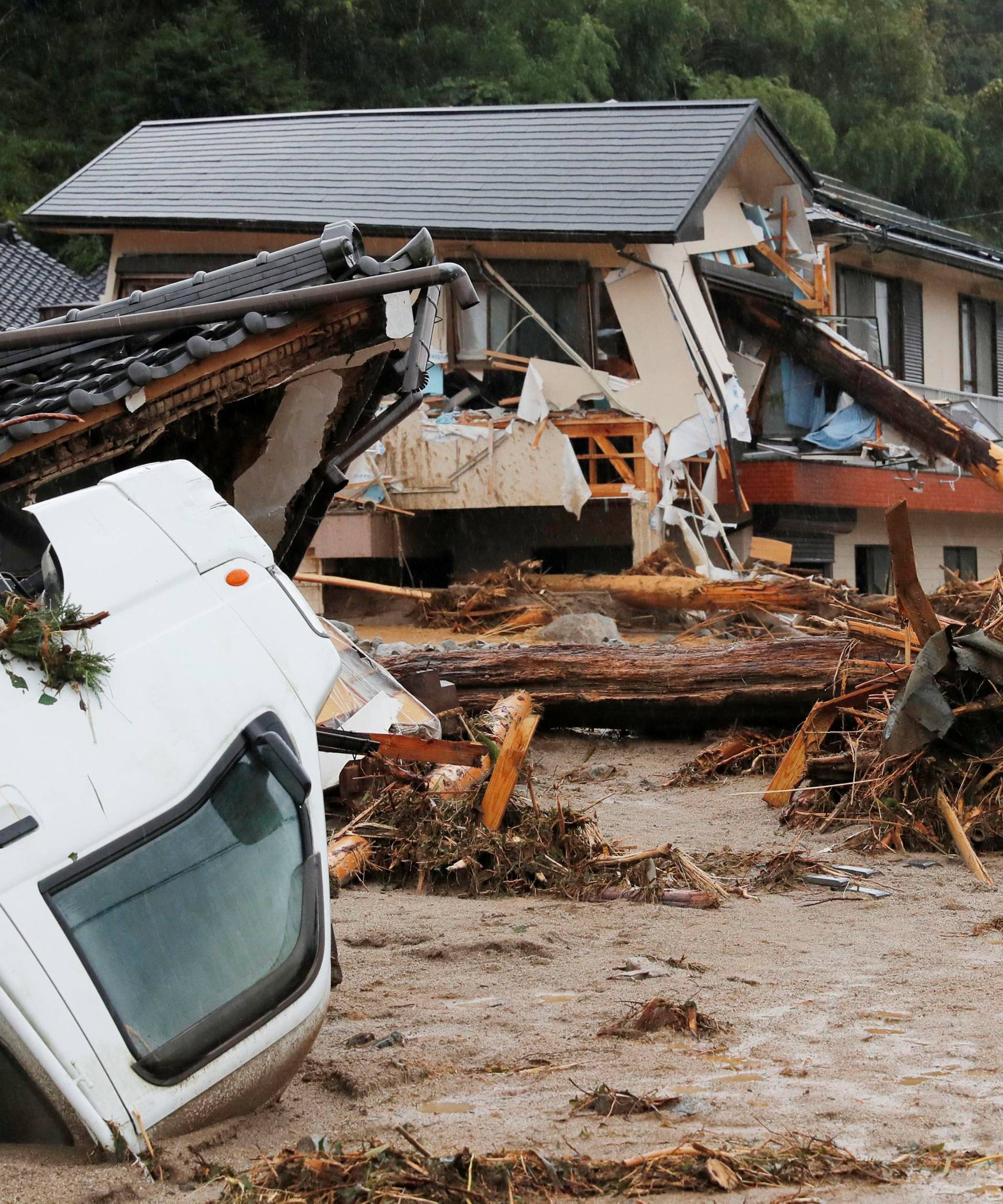 Houses and a vehicle are damaged by a swollen river after heavy rain hit the area in Asakura