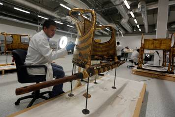 An Egyptian archaeological technician renovates the golden war wheel which belonged to King Tutankhamun, in the conservation centre of the Grand Egyptian Museum, on the outskirts of Cairo