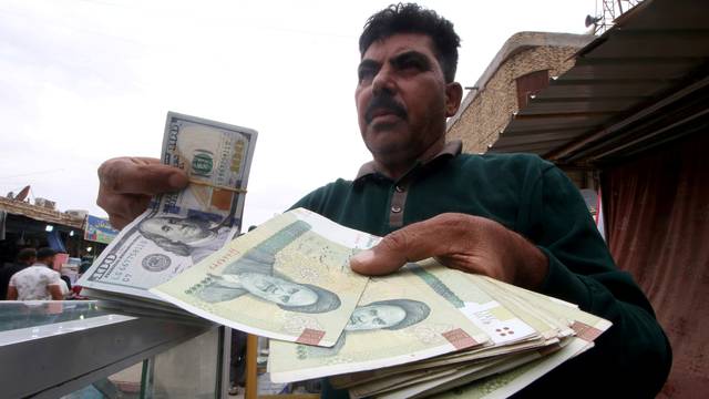 FILE PHOTO: A man holds Iranian rials at a currency exchange shop, before the start of the U.S. sanctions on Tehran, in Basra