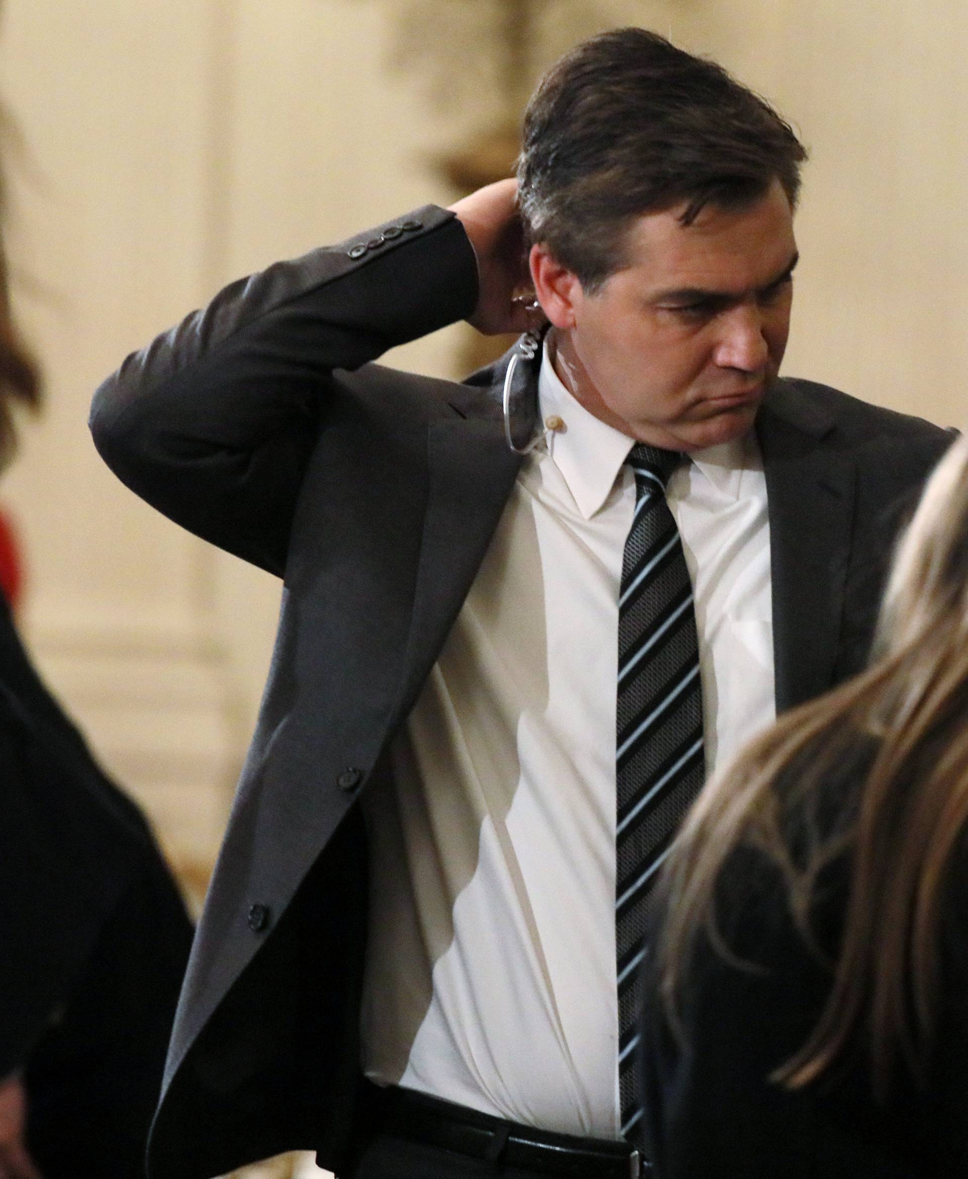 CNN's Acosta detaches earphone after tense exchange with U.S. President Trump during news conference at White House in Washington