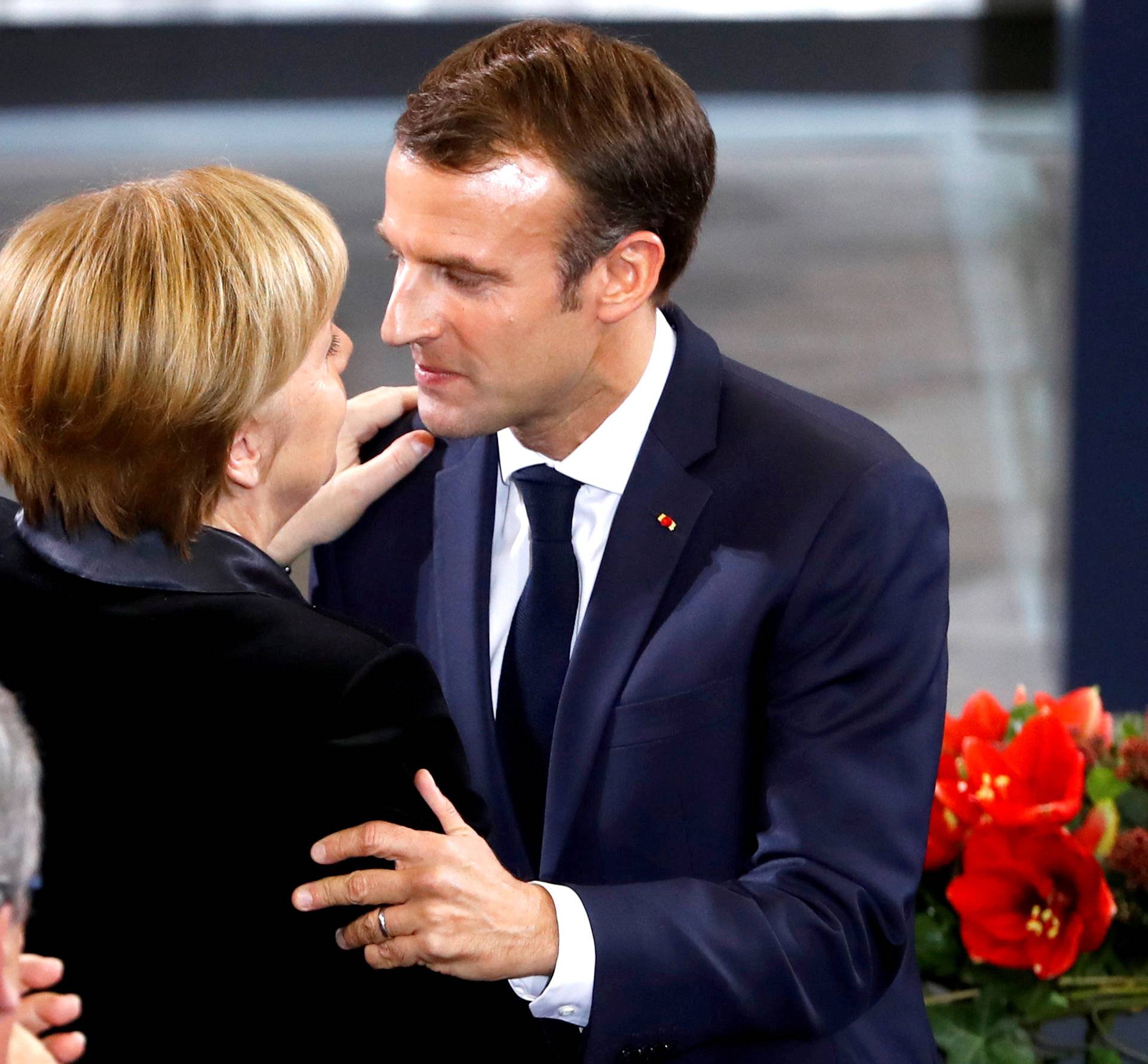 French President Emmanuel Macron hugs German Chancellor Angela Merkel after giving a speech during a ceremony at the lower house of parliament Bundestag in the Reichstag building in Berlin to mark National Mourning Day