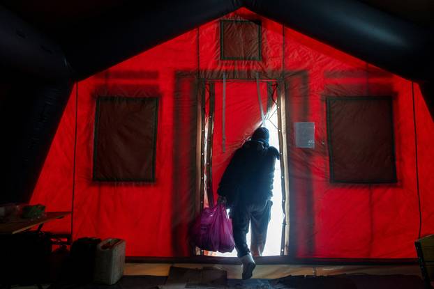 People warm up in a tent provided by emergency services for residents whose apartments are left without heating in Kyiv