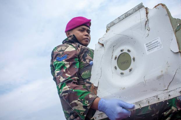 A soldier carries a part of the Lion Air flight JT610 airplane that crashed into the sea, as he walk at Tanjung Pakis beach in Karawang