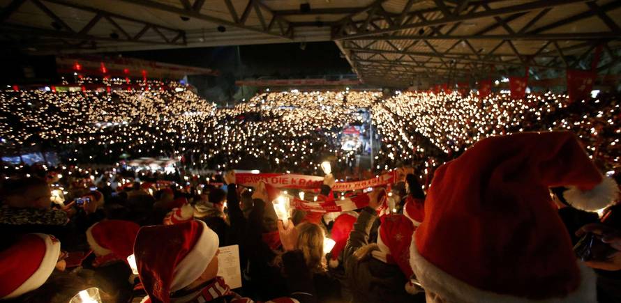People attend the "Weihnachtssingen", a candle-lit carol concert at the Alte Foersterei stadium in Berlin