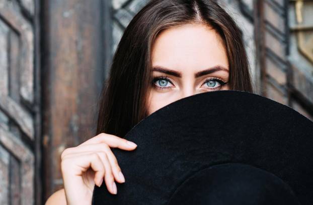 Portrait of a young pretty girl with a black hat in her arms