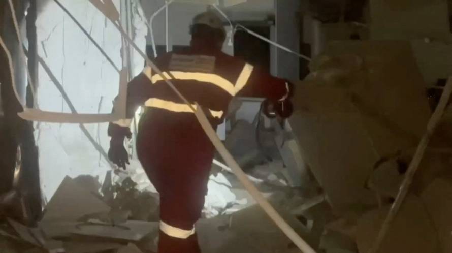 A member of the Iranian Red Crescent Society works at a site of a strike in a location given as Tehran