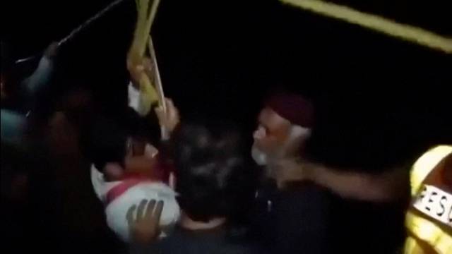 Rescuers pull a boy attached to a harness to safety after being rescued from a stranded cable car