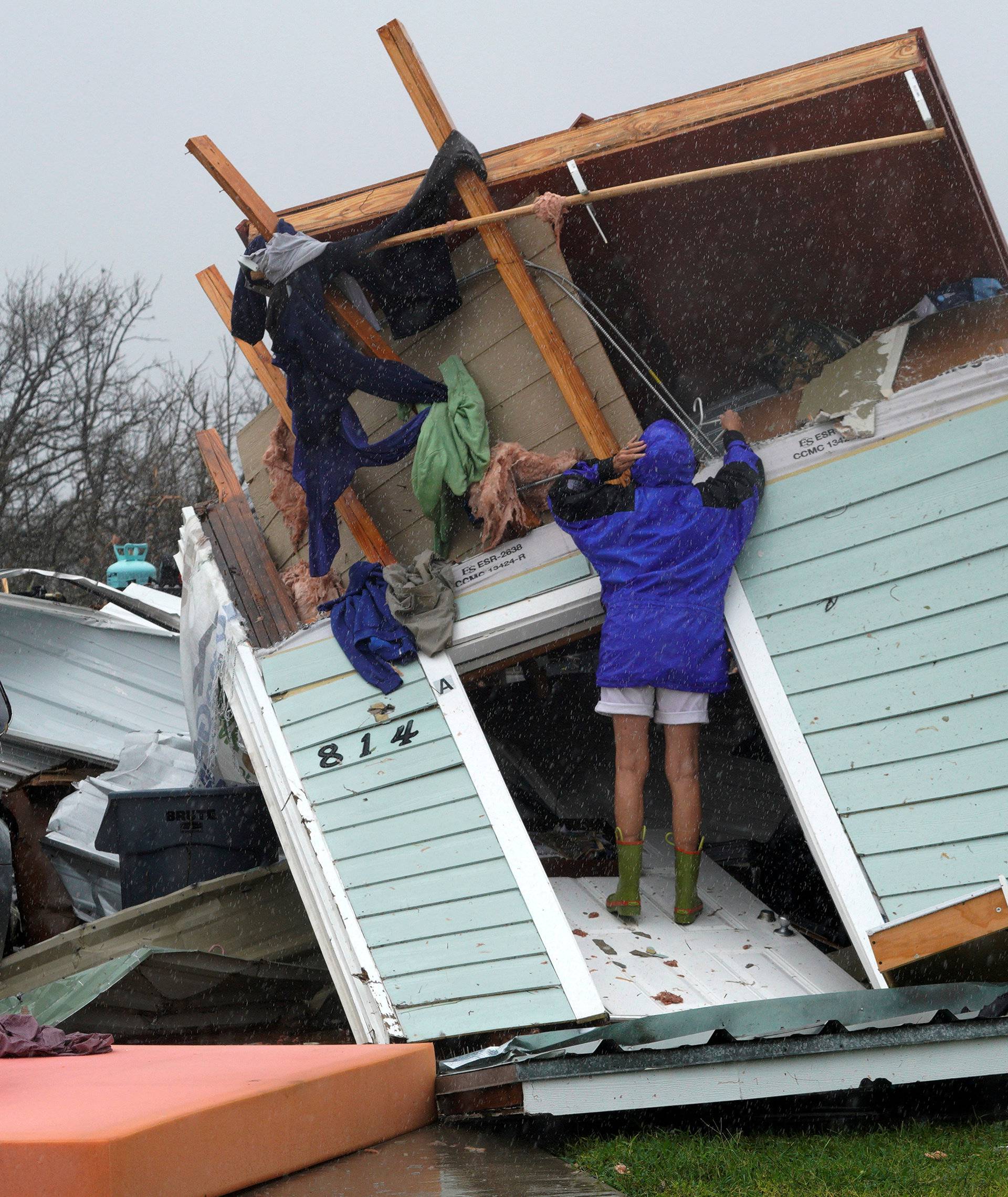 FILE PHOTO:    A woman uses a coat hanger to try and retrieve an item from a destroyed house after Hurricane Harvey struck Fulton