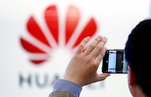 FILE PHOTO: A man takes a picture of a Huawei logo at the Huawei European Cybersecurity Center in Brussels