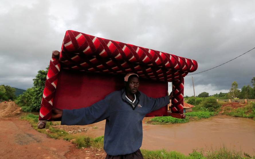 A man carries a sofa as he evacuates from his home after River Nzoia burst its banks and due to the backflow  from Lake Victoria, in Nyadorera, Siaya County