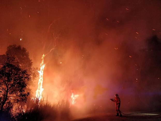 A supplied image shows firefighters battling a bushfire in Peregian Springs on the Sunshine Coast