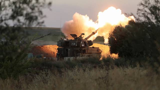Israeli soldiers work in an artillery unit as it fires near the border between Israel and the Gaza strip, on the Israeli side