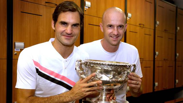 Roger Federer of Switzerland and his coach Ivan Ljubicic pose with the trophy after Federer won the Australian Open tennis tournament men's singles final, in the locker room in Melbourne