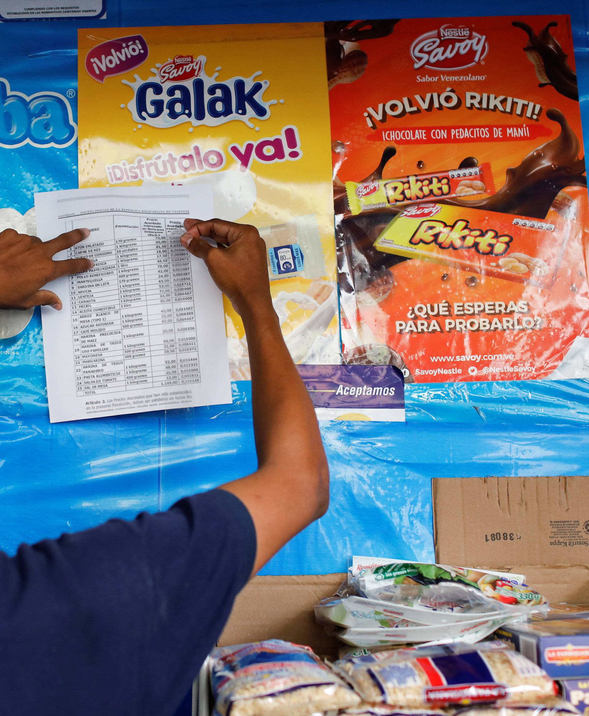 A man places a list with prices of products regulated by Venezuela's government in a mini market in Caracas