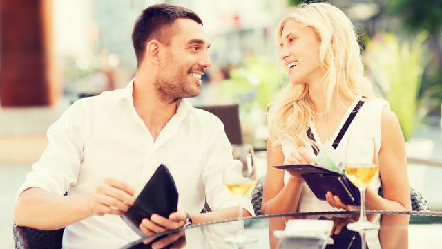 happy couple with wallet paying bill at restaurant