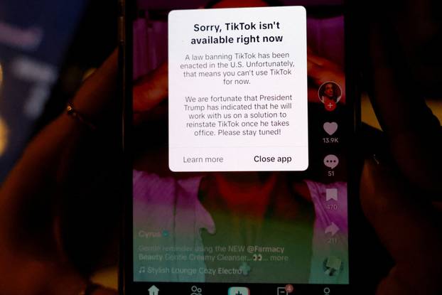 A woman poses with her smartphone displaying the TikTok app after it stopped working in the United States late on Saturday