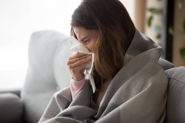 Ill,Upset,Young,Woman,Sitting,On,Sofa,Covered,With,Blanket