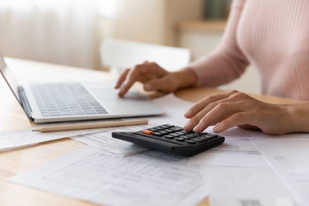 Close,Up,Cropped,Woman,Planning,Budget,,Using,Laptop,And,Calculator,