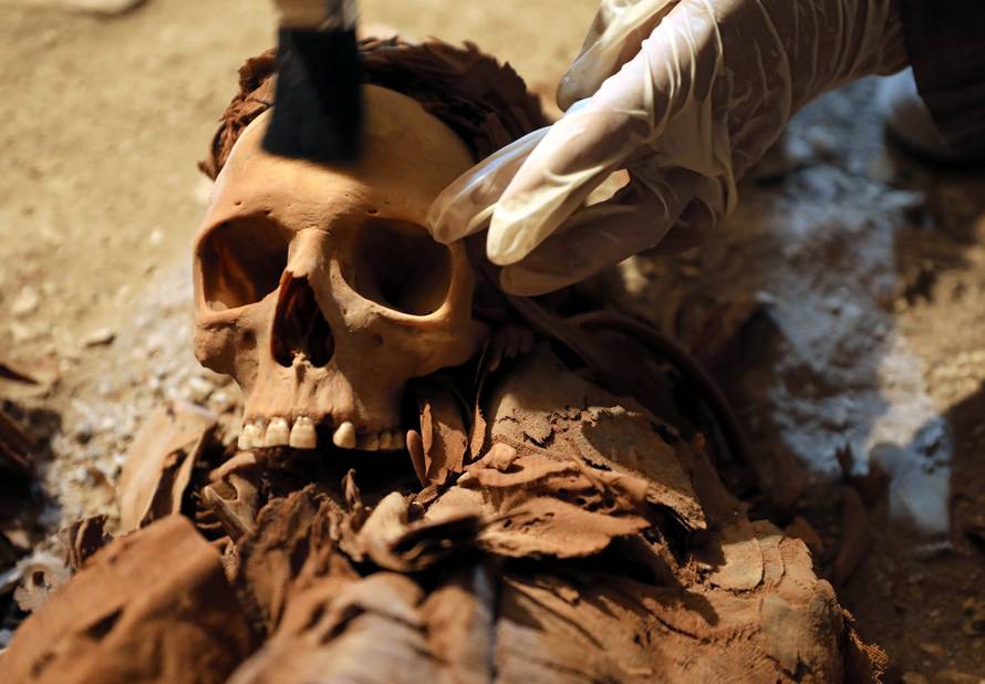 Egyptian antiquities worker brushes a skull in a recently discovered tomb of Amenemhat, a goldsmith from the New Kingdom at the Draa Abu-el Naga necropolis near the Nile city of Luxor, south of Cairo