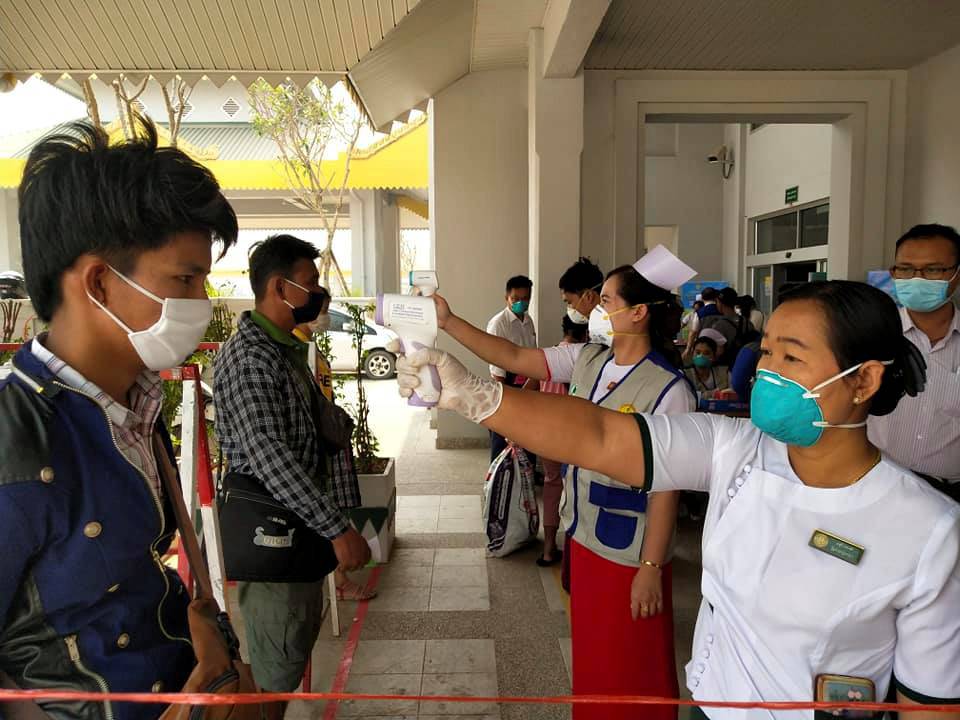 Migrant workers from Myanmar get their temperatures taken by healthcare workers at the Myawaddy border office after passing through border gate at Myawaddy, Myanmar