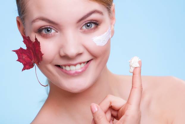 Skin care. Face of young woman girl with red maple leaf.