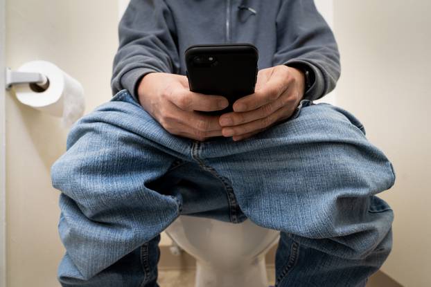 Close up of a man in toilet using cellphone