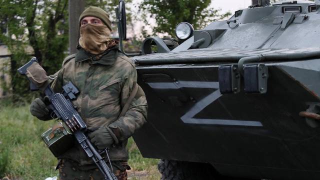 Service members of pro-Russian troops stand guard in Mariupol