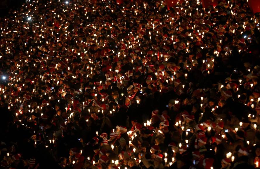 People attend the "Weihnachtssingen", a candle-lit carol concert at the Alte Foersterei stadium in Berlin