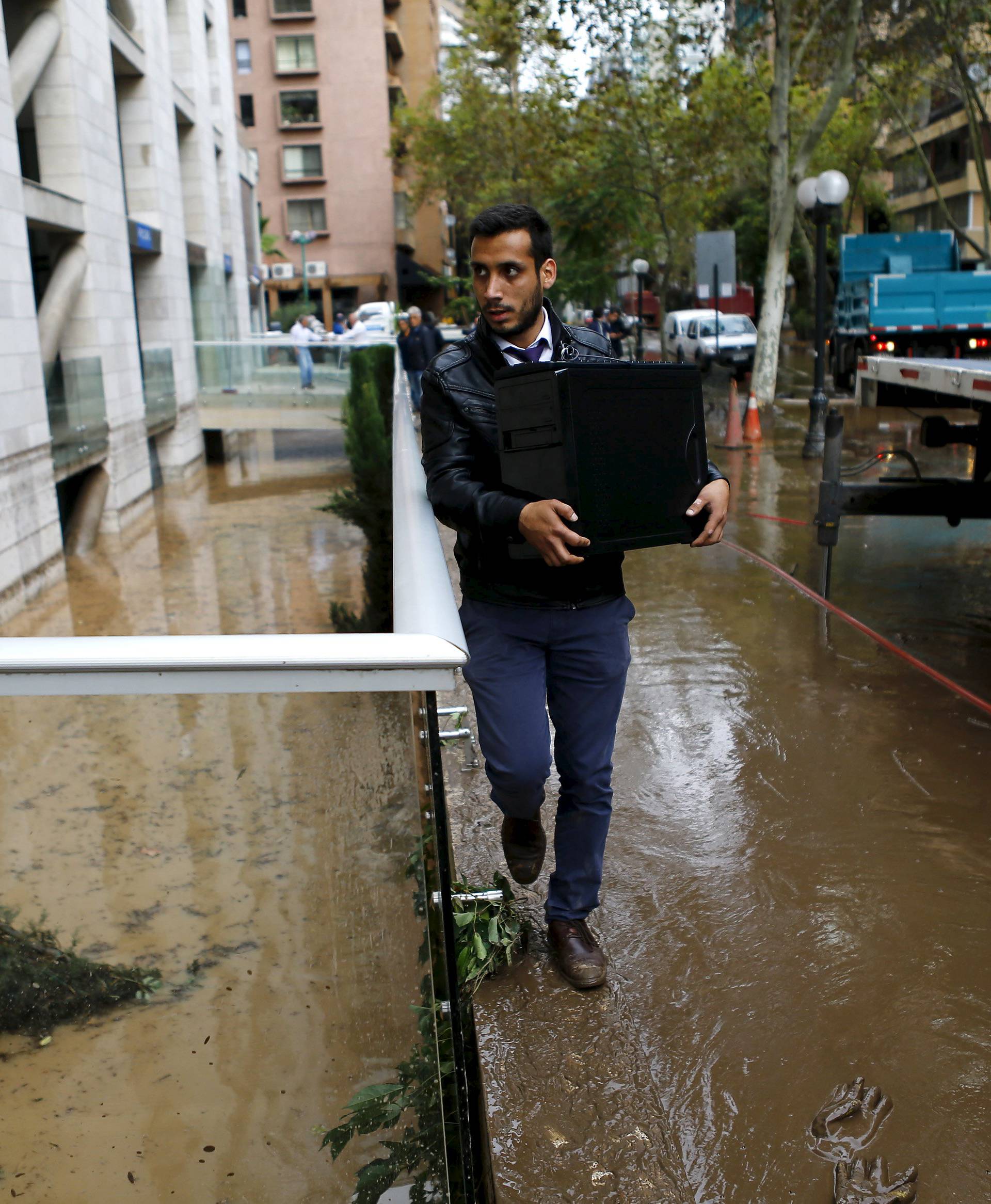 A man carries a computer CPU in a flooded street after in Santiago