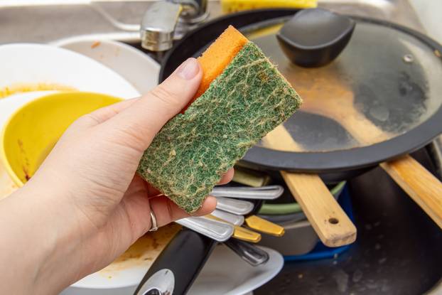Woman,Holds,Orange,Sponge,For,Washing,Dishes.,The,Kitchen,Sink