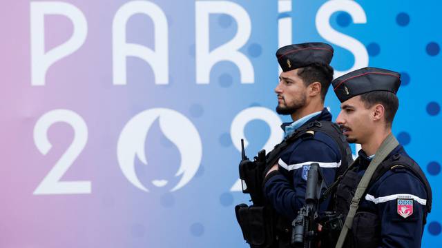 French gendarmes walk past the logo of the Paris 2024 Olympic and Paralympic Games in front of the National Assembly in Paris