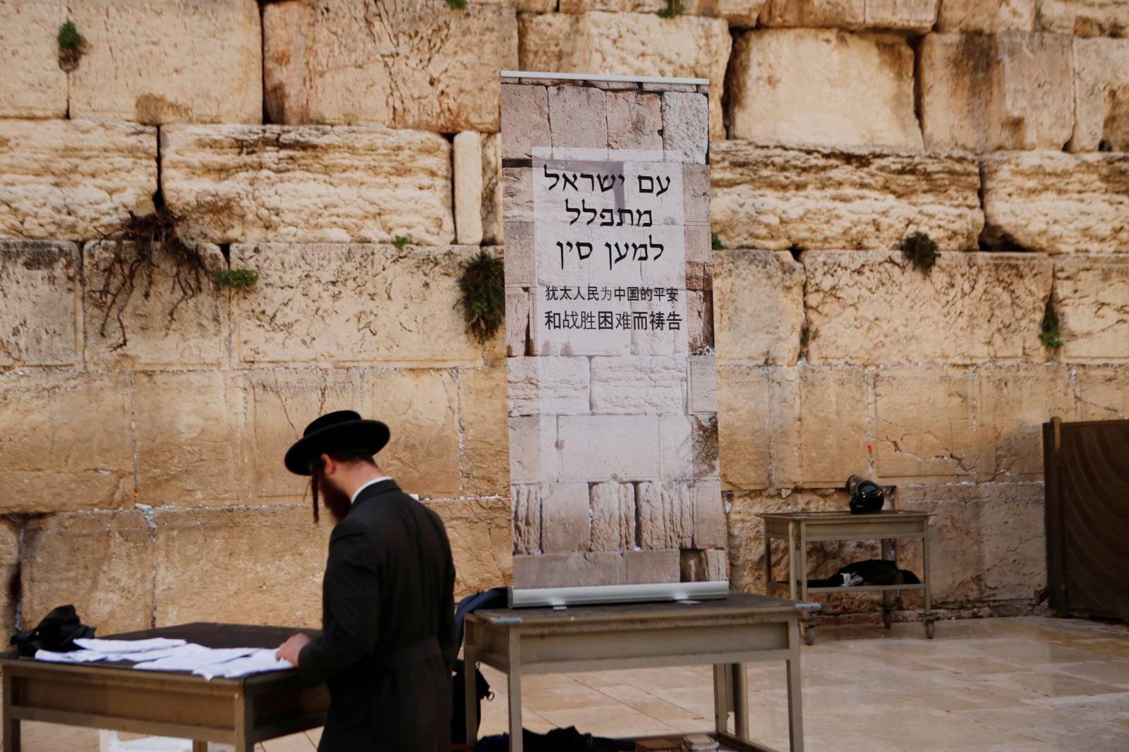 A Jewish worshipper prays next to a placard at the Western Wall in Jerusalem's Old City