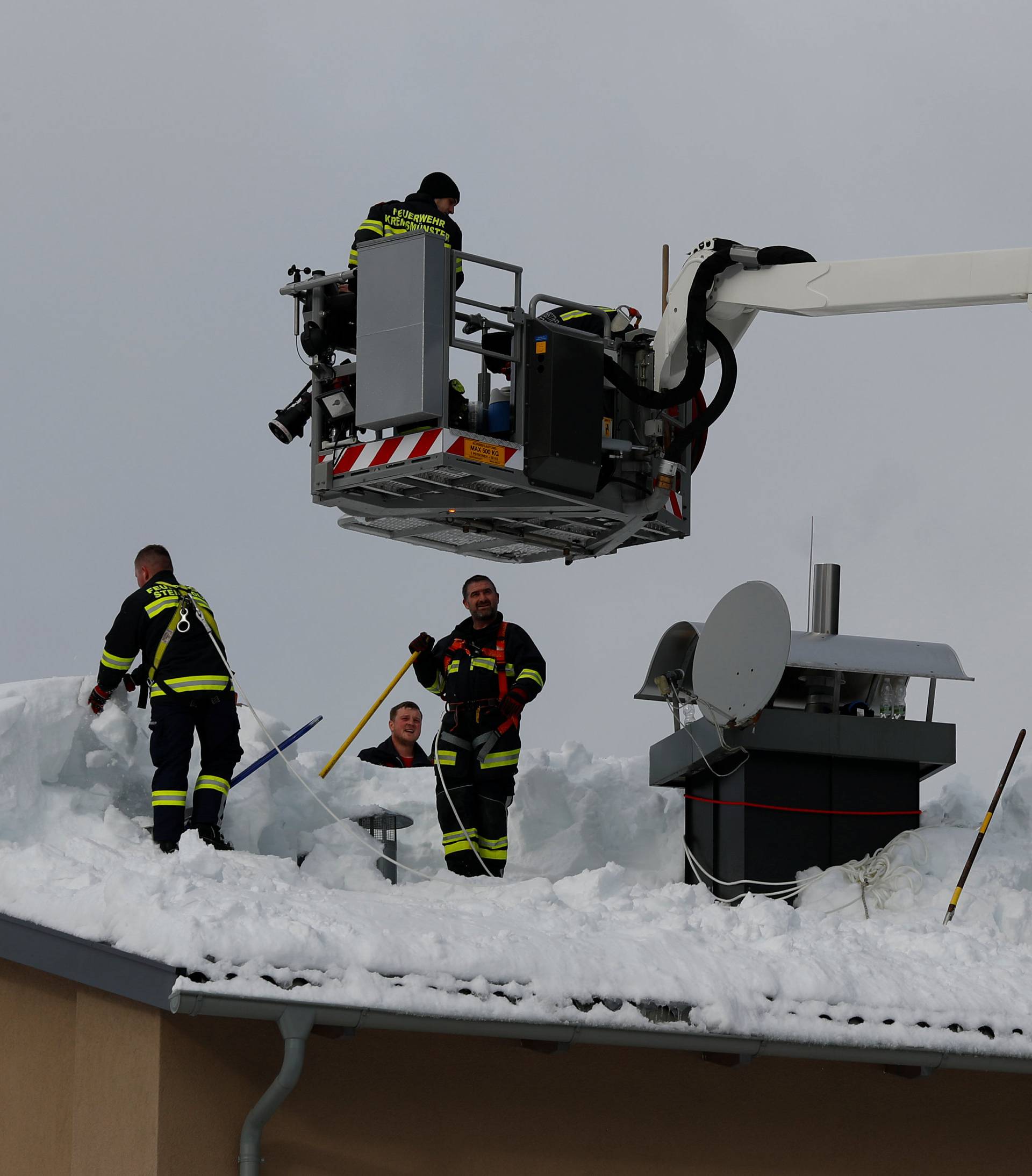 Members of the fire brigade shovel snow on a rooftop after heavy snowfall in Rosenau