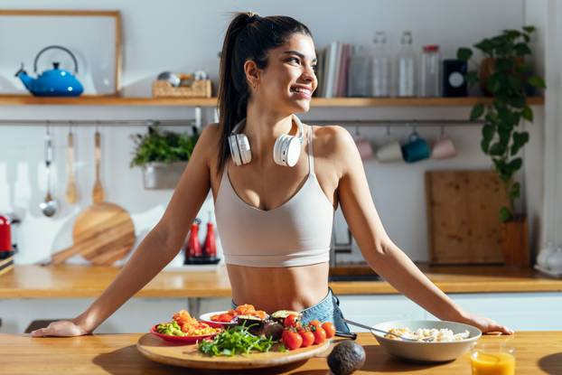 Fintess woman making a healthy poke bowl in the kitchen at home.