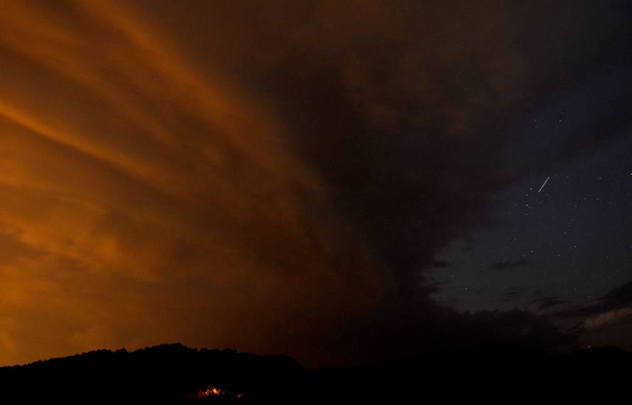 A meteor streaks past stars in cloudy night sky during the annual Perseid meteor shower, near Skopje, Macedonia