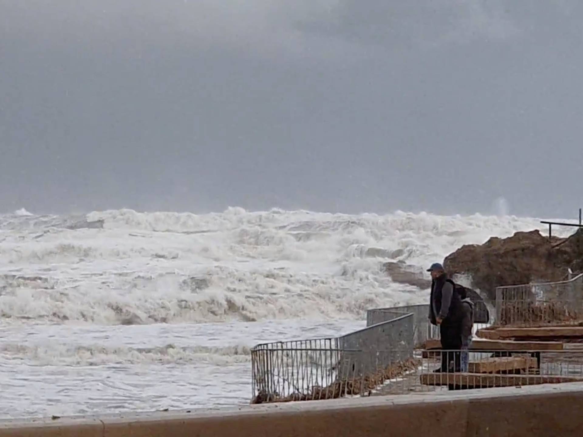 People watch as waves from Storm Gloria crash onto the shore in Javea