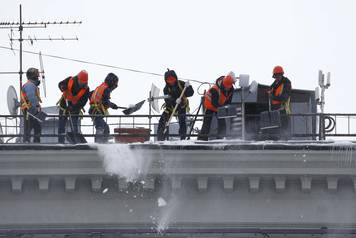 Workers remove snow from the roof of a building in central Moscow