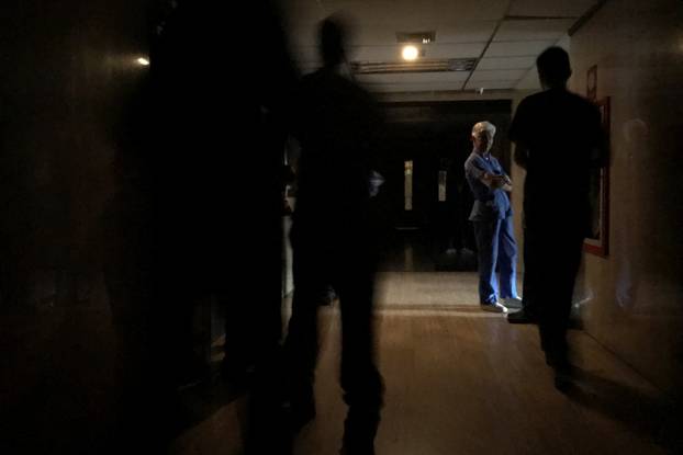 People wait at the emergency area of a clinic during a blackout in Caracas