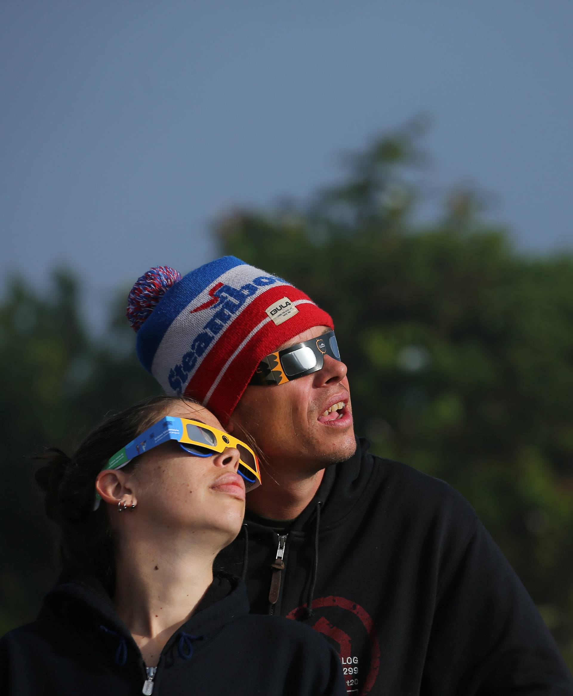 People try on solar viewing glasses as the sun emerges through fog cover before the solar eclipse in Depoe Bay