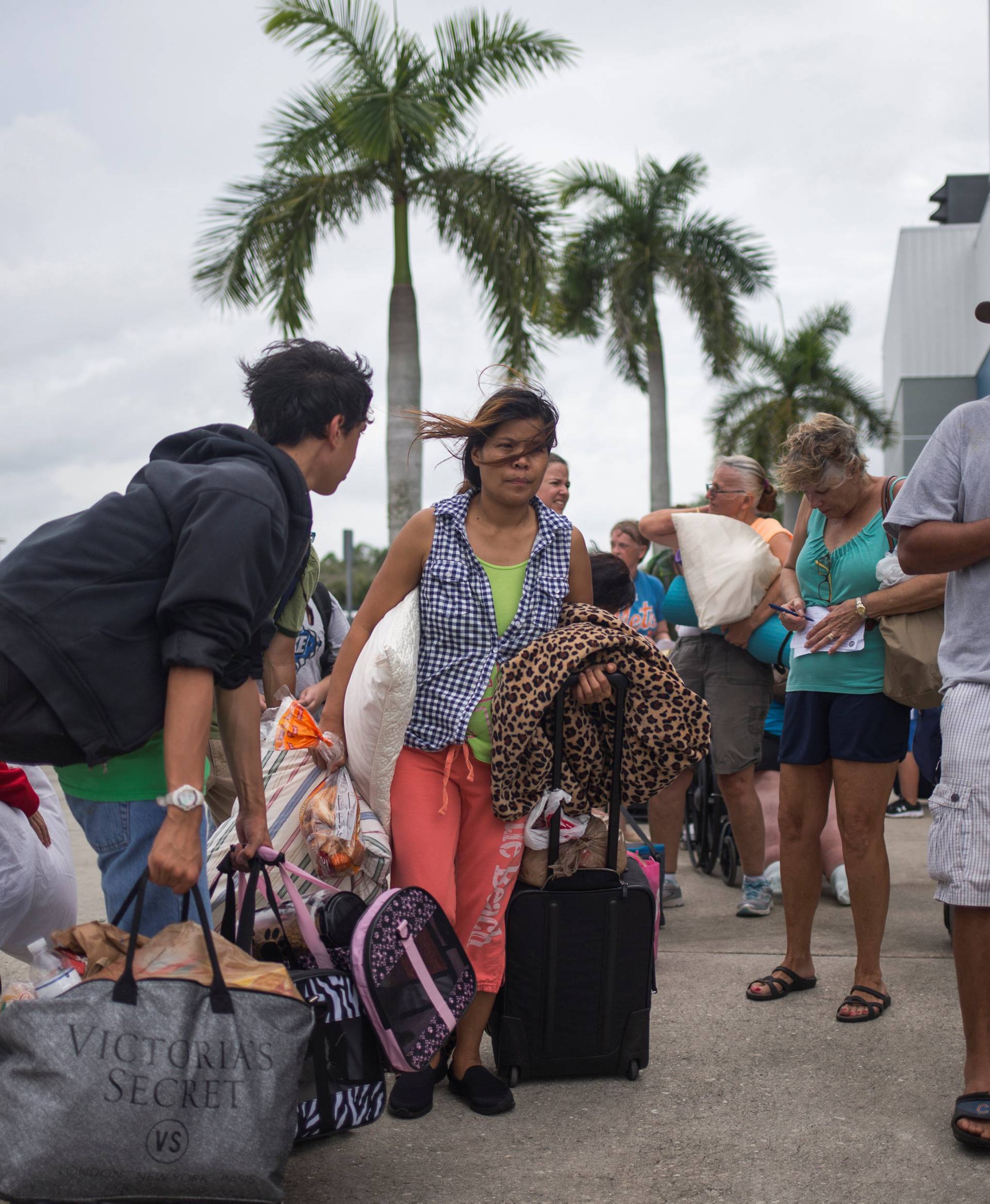 Residents carry their belongings into a shelter ahead of the downfall of Hurricane Irma in Estero, Florida