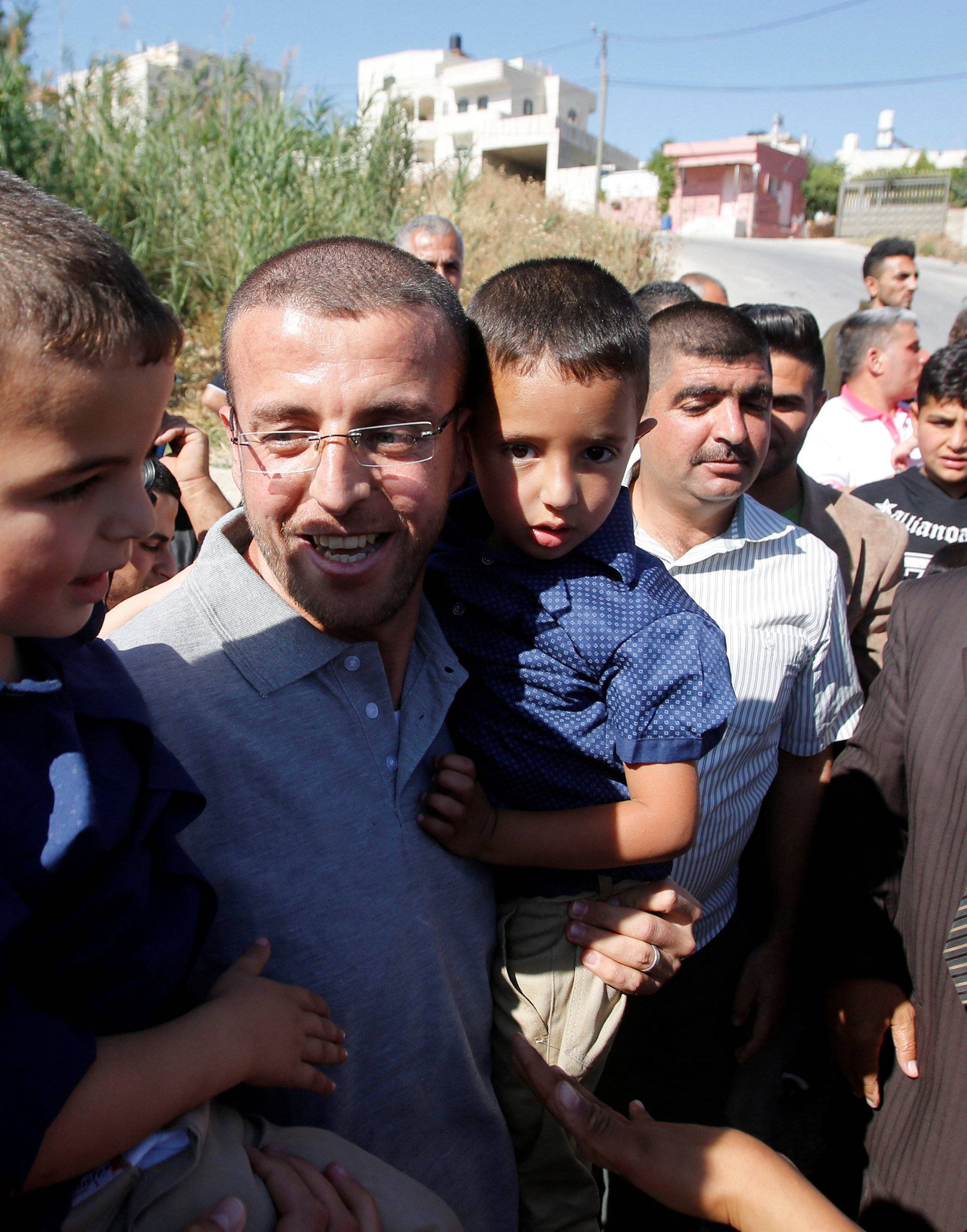 Freed Palestinian journalist Mohammad al-Qiq, who was detained by Israel last November and went on 94-day hunger strike to protest against his detention without charge, holds his children upon his release in the West Bank town of Dura