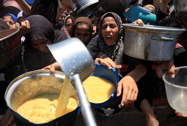 Palestinians wait to receive food from a charity kitchen, in Gaza City