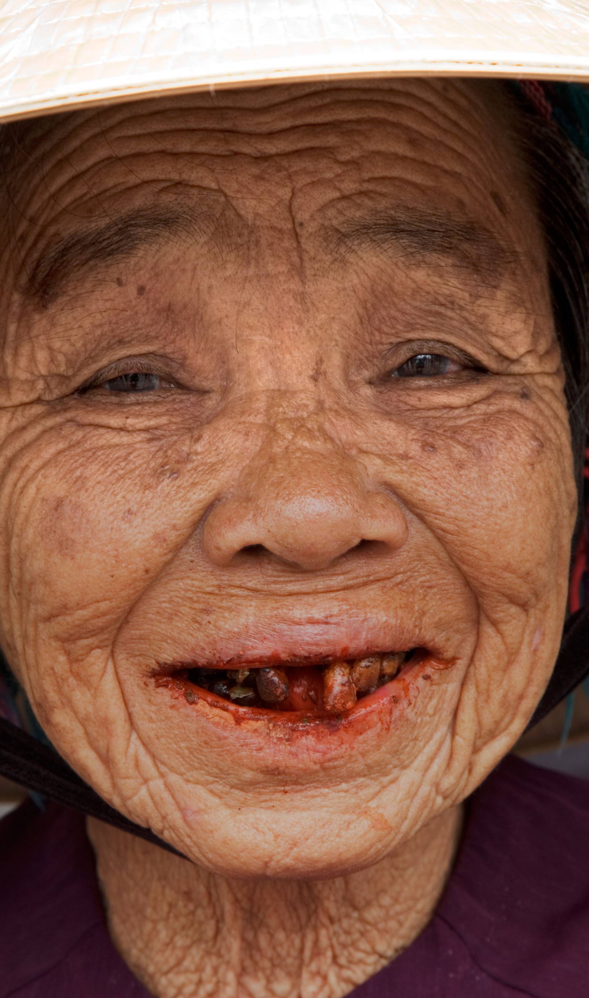 Aged woman with red betel nut stains in her mouth, Hoi An, Vietnam